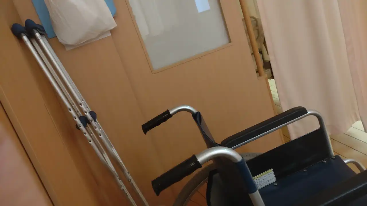 病院のベッド脇のブースに置かれた車椅子と松葉杖